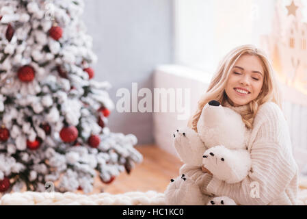 Happy dreamy woman hugging her stuffed bear Stock Photo