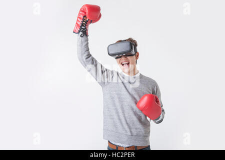 Young smiling Korean man wearing virtual reality headset holding his hands in boxing gloves Stock Photo
