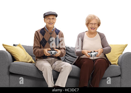 Cheerful seniors sitting on a sofa and playing video games isolated on white background Stock Photo