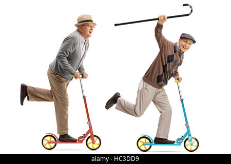 Full length portrait of two overjoyed seniors riding scooters isolated on white background Stock Photo