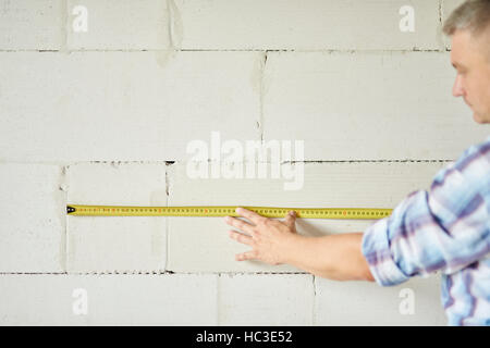 Senior carpenter measuring wall by meter Stock Photo