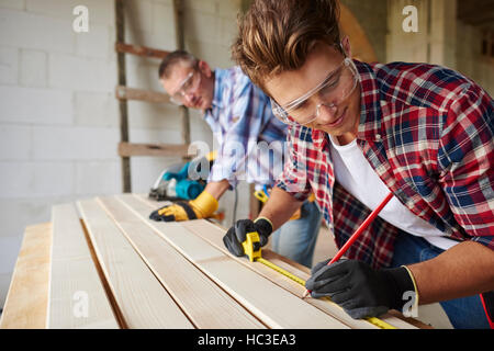 Younger carpenter is helping the older one Stock Photo