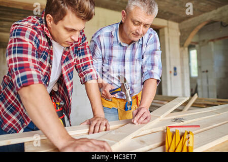 Close up of carpenters with hammer hitting planks Stock Photo