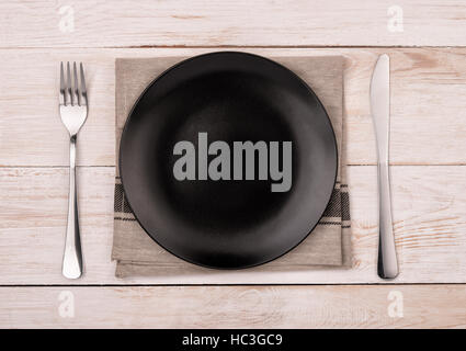Top view of empty black  plate, silverware and napkin on wooden table background Stock Photo