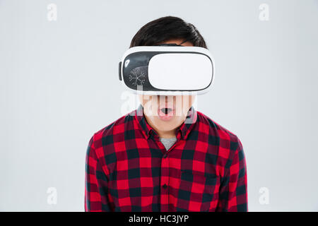 Image of surprised man dressed in casual shirt in a cage and wearing virtual reality device. Isolated over white background. Look at camera. Stock Photo