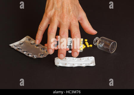 a woman collects too many tablets from jars and blisters /a woman abusing medicines Stock Photo