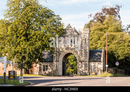 England, Market town of Tenterden in Kent. Gothic 1930's Gatehouse to 'Heronden Hall', with trees on either side. Bright sunshine. Stock Photo