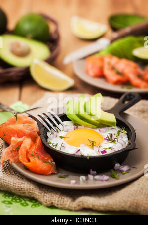 Fried egg, avocado and smoked salmon in frying pan served for breakfast Stock Photo