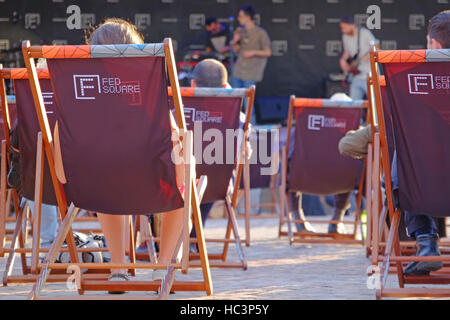 People in deck chairs watching free entertainment in Federation Square, Melbourne,Australia Stock Photo