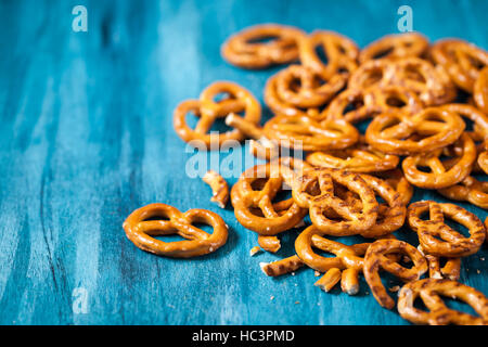 Salty snacks mini pretzels on blue wooden table Stock Photo