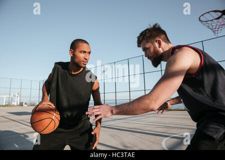 Two young sportsmen playing basketball at the playground Stock Photo