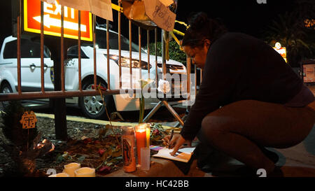Oakland, USA. 7th Dec, 2016. A woman writes notes to mourn the victims of a warehouse fire in Oakland, California, the United States, Dec. 7, 2016. The death toll of the worst fire in the history of Oakland stood at 36. Credit:  Xu Yong/Xinhua/Alamy Live News Stock Photo