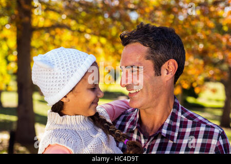 Smiling father carrying daughter at park Stock Photo
