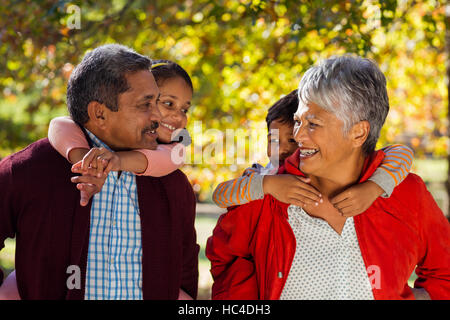 Grandparents piggybacking grandchildren at park Stock Photo