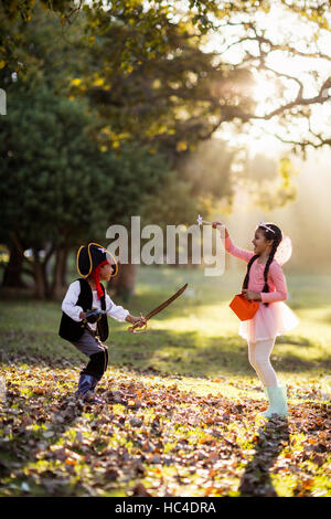 Side view of playful siblings wearing costumes at park Stock Photo