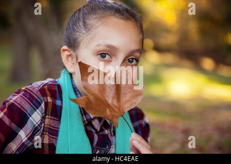 Portrait of girl hiding mouth with autumn leaf Stock Photo