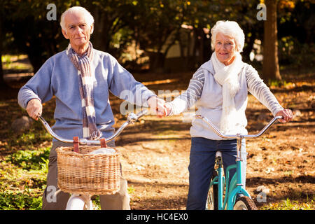 Senior couple riding their bike and holding their hands Stock Photo