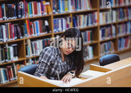 Female student writing notes in library Stock Photo