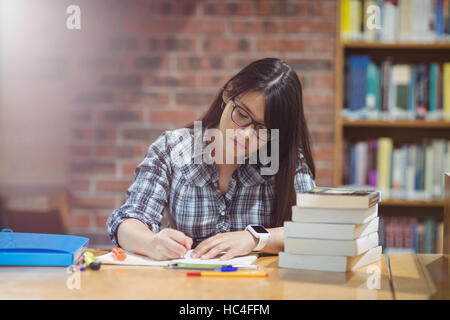 Female student writing notes in library Stock Photo
