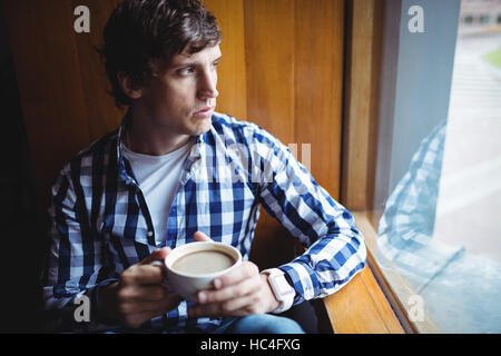 Student looking through window while having coffee Stock Photo