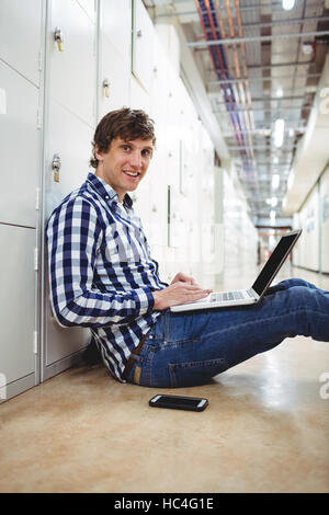 Student using laptop in locker room Stock Photo