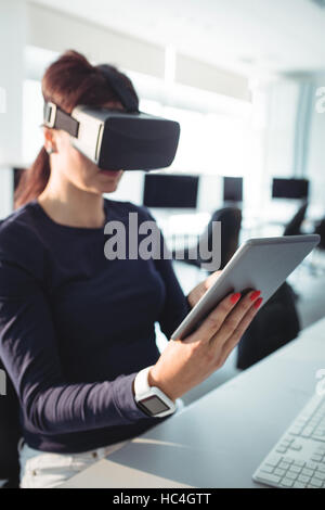 Mature student in virtual reality headset using digital tablet Stock Photo
