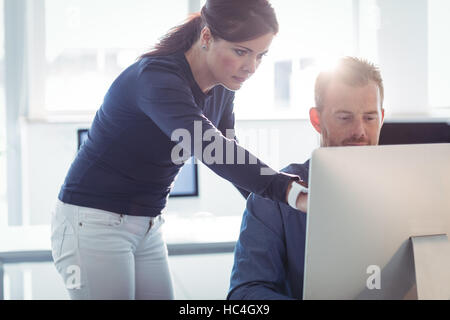Teacher assisting mature student in computer room Stock Photo