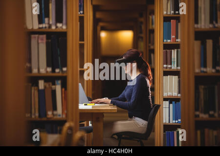 Mature student in virtual reality headset using laptop Stock Photo