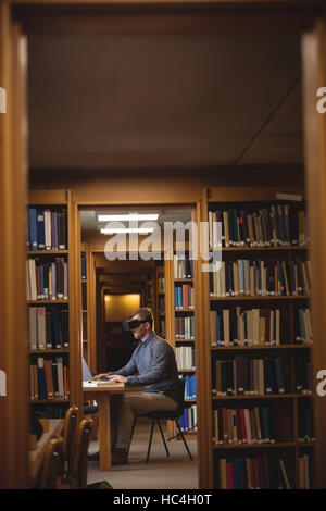 Mature student in virtual reality headset using laptop Stock Photo