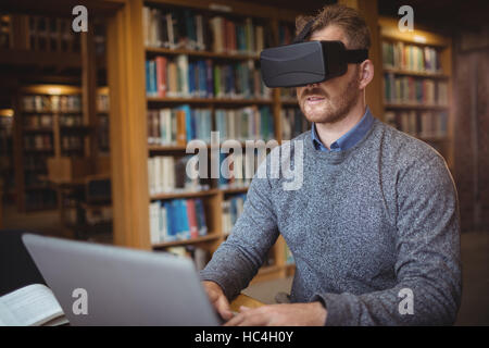 Mature student in virtual reality headset using laptop Stock Photo