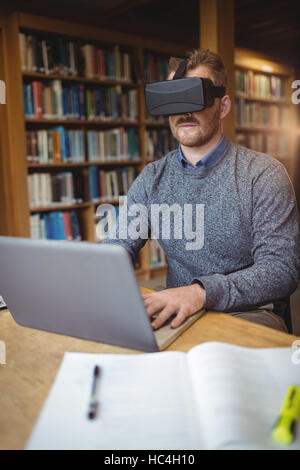 Mature student in virtual reality headset using laptop Stock Photo