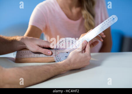 Physiotherapist examining female patients wrist with goniometer Stock Photo