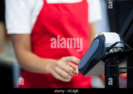 Female staff using credit card terminal at cash counter Stock Photo