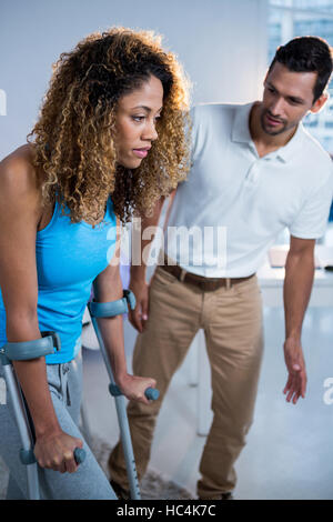 Physiotherapist helping his patient walking with crutch Stock Photo