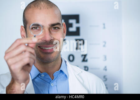 Male optometrist looking through magnifying glass Stock Photo