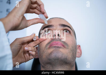 Optometrist putting drops into patients eyes Stock Photo