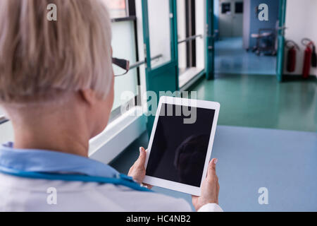 Doctor using digital tablet in corridor Stock Photo