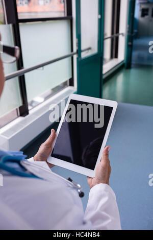 Doctor using digital tablet in corridor Stock Photo