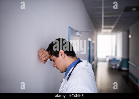 Sad doctor leaning against the wall Stock Photo