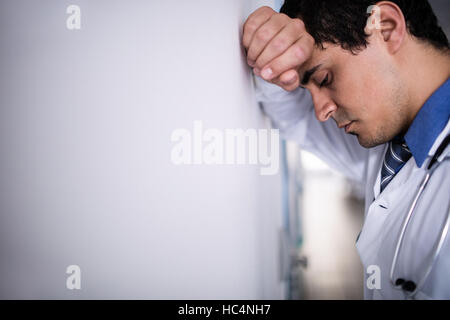 Sad doctor leaning against the wall Stock Photo