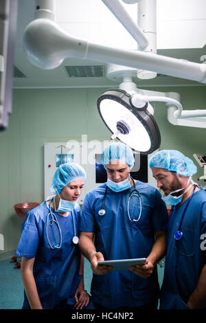 Surgeons discussing over digital tablet in operation room Stock Photo