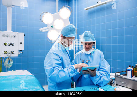 Surgeons discussing over digital tablet in operation room Stock Photo