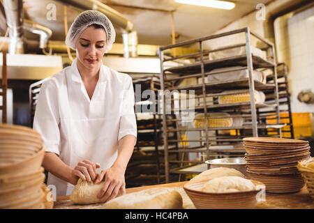 Female baker kneading a dough Stock Photo