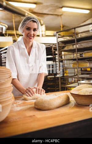 Female baker kneading a dough Stock Photo