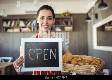 Portrait of female baker holding open signboard Stock Photo