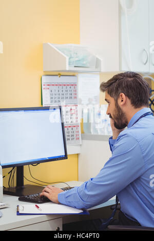 Doctor talking on phone while using computer Stock Photo