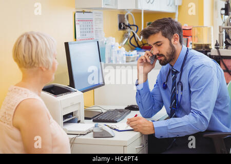 Doctor sitting at his desk and talking on phone Stock Photo