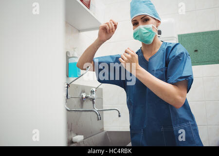 Portrait of female surgeon washing hands prior to operation using correct technique for cleanliness Stock Photo