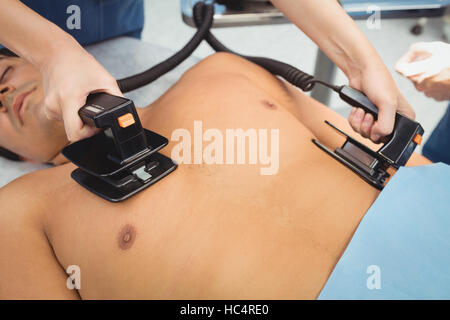 Female surgeon resuscitating an unconscious patient with a defibrillator Stock Photo