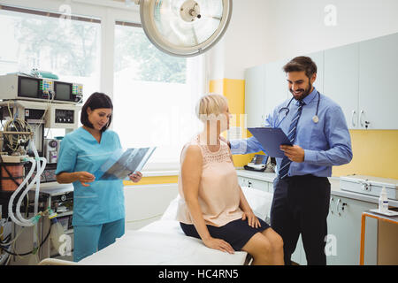 Male doctor interacting with a patient while nurse looking at x-ray Stock Photo